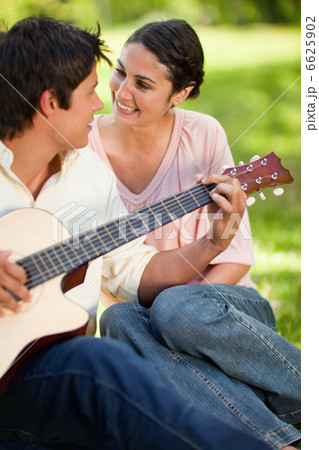 Man playing a guitar while looking at his friend Man playing a guitar while looking at his friend 6625902