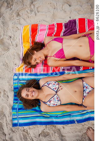 Overhead view of smiling attractive women tanning in the sun 6626100