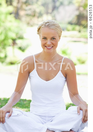 Smiling woman in a yoga position on the lawn 6626553
