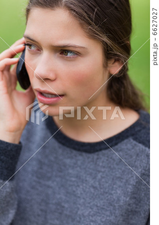 Young serious girl talking on the phone while looking towards th Young serious girl talking on the phone while looking towards th 6627027