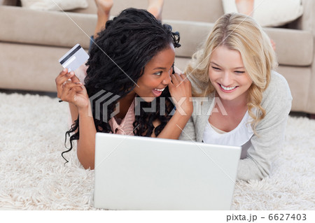 A woman holding a bank card is is smiling at her friend who has A woman holding a bank card is is smiling at her friend who has 6627403