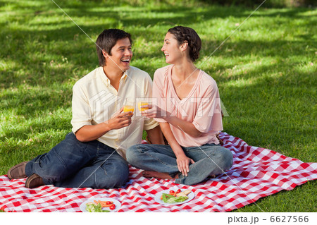 Two friends laughing while raising their glasses during a picnic Two friends laughing while raising their glasses during a picnic 6627566