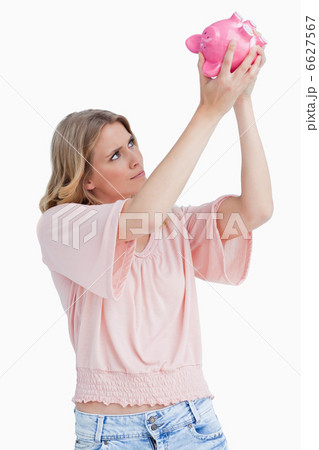 Woman looking inside of a piggy bank 6627567