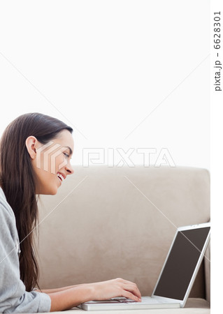 A laughing woman lying on her couch with her laptop 6628301