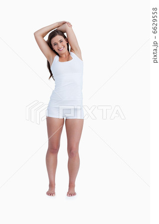 Smiling woman standing with arms crossed above her head 6629558