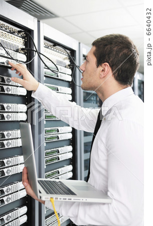businessman with laptop in network server room 6640432