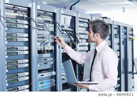 businessman with laptop in network server room 6640921