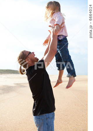 Father throwing daughter in the air at the beach 6664014
