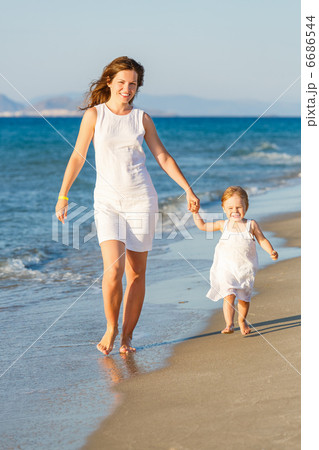 Mother and daughter walking on the beach 6686544