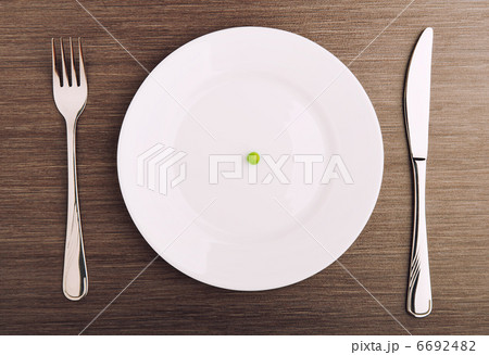 diet concept. one pea on an empty white plate diet concept. one pea on an empty white plate 6692482