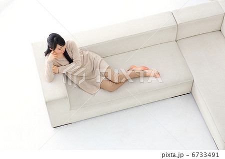 白いソファに寝る女性 俯瞰 の写真素材