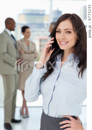 Smiling businesswoman talking on the phone with one hand on her 6773245