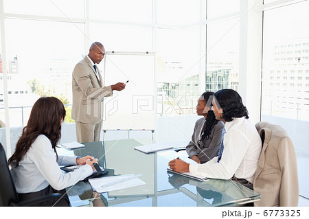 Businessman pointing to something on the flipchart to explain th 6773325