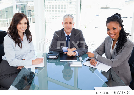 Mature director sitting at the desk and accompanied by two busin 6773330