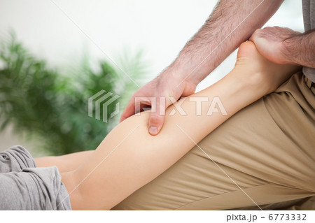 Man massaging the leg of a woman while placing it on his thigh 6773332