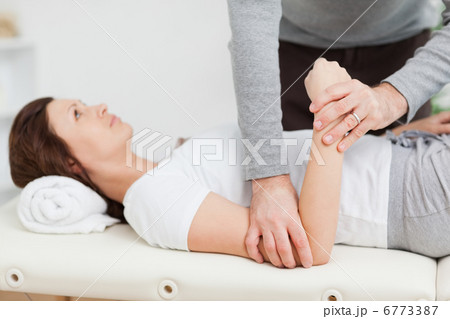Physiotherapist manipulating the arm of a peaceful woman 6773387