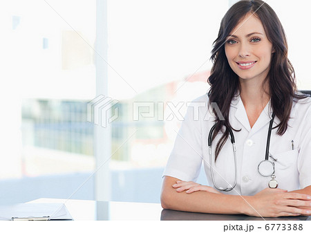 Young smiling doctor sitting at the desk near a clipboard 6773388