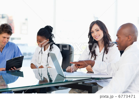 Two smiling medical interns working at the computer near colleag 6773471