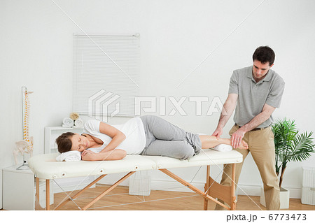 Woman lying on her side while being massaged by a man 6773473