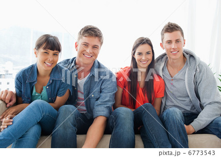 Smiling group on the couch looking at the camera while leaning f 6773543
