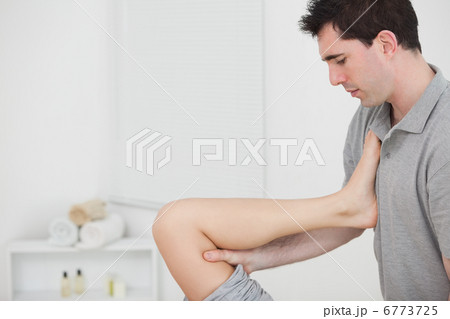 Chiropractor raising the leg of his patient against his chest 6773725