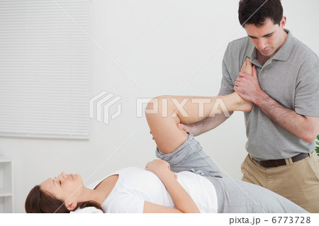 Doctor stretching the leg of woman while raising her leg against 6773728