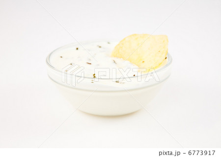 Bowl of dip with herbs with a chip dipped in it 6773917