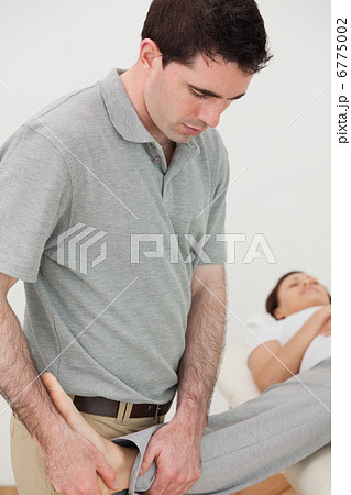 Physio stretching the leg of a woman while looking at her foot 6775002