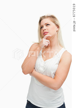 Blonde woman placing her fingers on her chin while crossing her 6775019