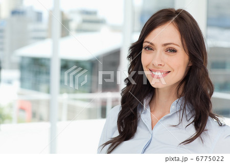 Young smiling executive woman standing upright in front of the w 6775022