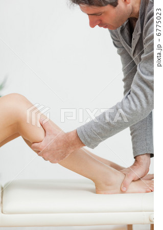 Serious osteopath holding the calf of a patient 6775023