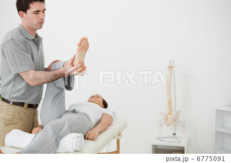 Brunette physiotherapist manipulating the leg of a woman 6775091