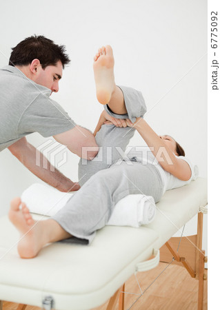 Brown-haired woman lying while stretching her leg 6775092