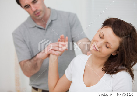 Woman sitting while being stretched by a physiotherapist 6775110