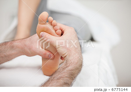 Man using his two hands to massage a foot 6775144