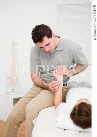 Serious physiotherapist moving the wrist of a woman 6775149