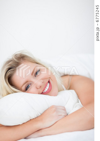 Young woman smiling while embracing a pillow 6775245