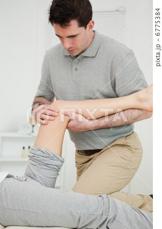 Serious physiotherapist looking at the knee of a patient Serious physiotherapist looking at the knee of a patient 6775384