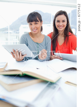 Two students with tablets in their hands as they sit and do home 6775412