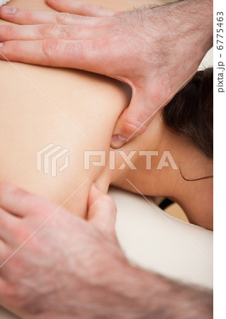Chiropractor massaging the shoulders of his patient while using 6775463