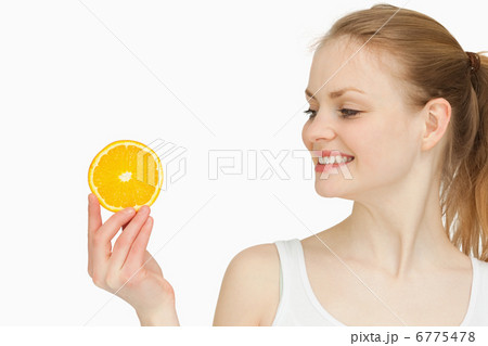Woman presenting an orange slice while looking at it Woman presenting an orange slice while looking at it 6775478