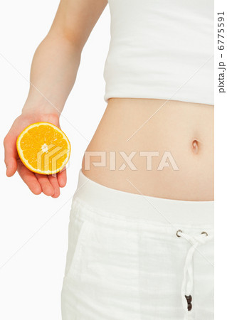 Close up of a woman placing an orange near her belly Close up of a woman placing an orange near her belly 6775591