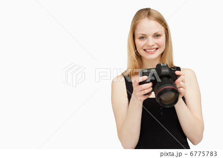 Woman holding a SLR camera while smiling Woman holding a SLR camera while smiling 6775783