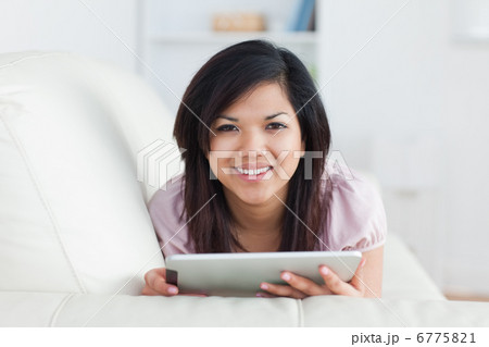 Woman smiling while resting on a couch and playing with a tablet Woman smiling while resting on a couch and playing with a tablet 6775821
