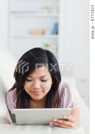 Woman lying on a sofa while looking at a tablet Woman lying on a sofa while looking at a tablet 6775825