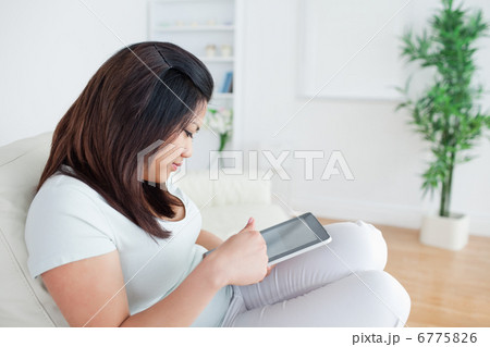 Woman sitting on a sofa while holding and playing with a tactile Woman sitting on a sofa while holding and playing with a tactile 6775826