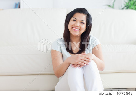 Woman smiles as she sits on the floor in a living room Woman smiles as she sits on the floor in a living room 6775843
