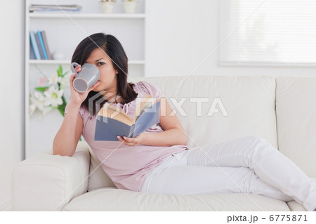Woman drinking from a mug while lying on a sofa 6775871