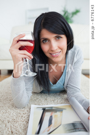 Woman smiling while holding a magazine and a glass of red wine Woman smiling while holding a magazine and a glass of red wine 6776143
