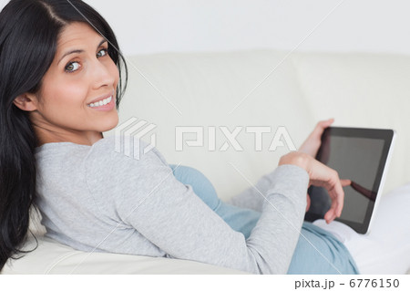 Woman touching a tablet screen while sitting on a couch 6776150